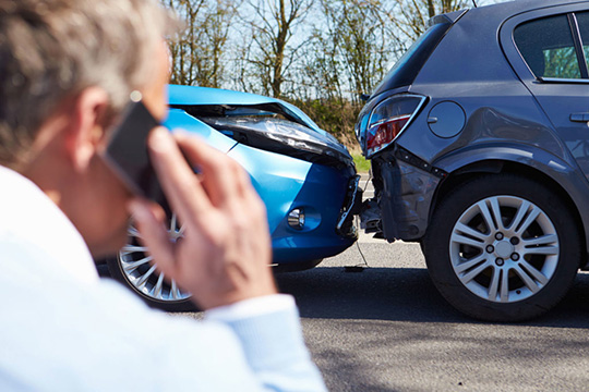 man calling ambulance on phone after car accident