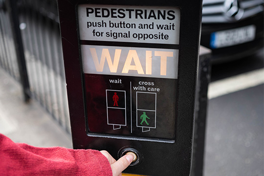pedestrian pressing button at pedestrian crossing