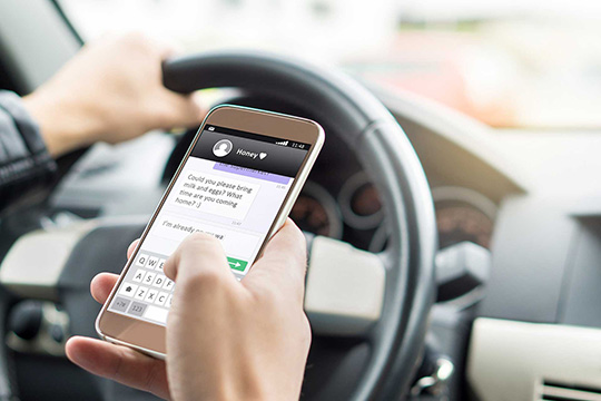 man texting on phone whilst driving