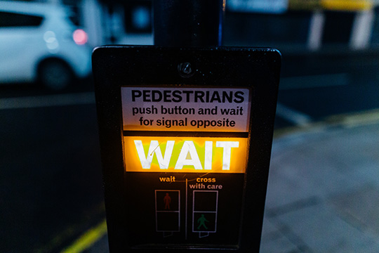 yellow wait warning sign at a pedestrian crossing