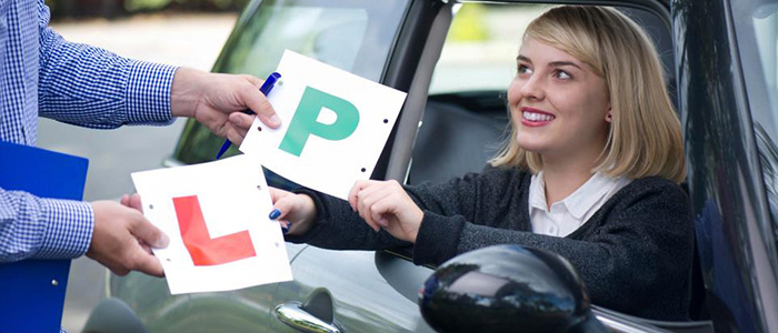 driving instructor and young lady driver swapping l plates for p plates