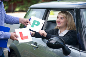 driving instructor and learner driver swapping l plates for p plates