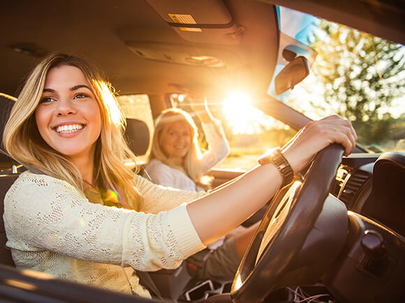 young female driver with mother in car smiling looking out of driver side window