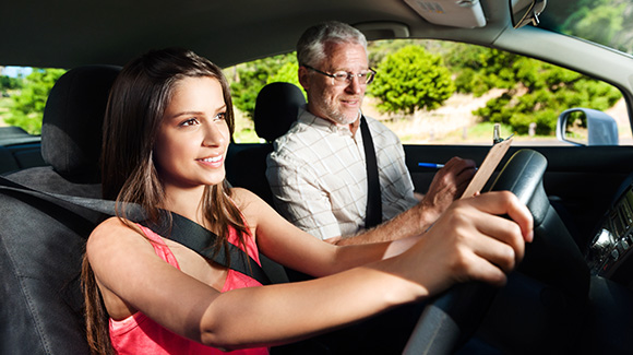 driving instructor taking notes with happy young female driver