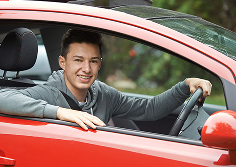 happy young male driver smiling in red car