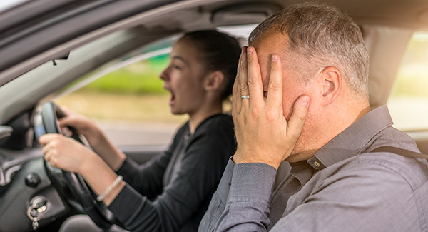 scared father giving nervous teenage daughter driving lesson 