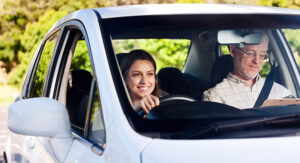 Happy and confident learner driver driving a car with an instructor