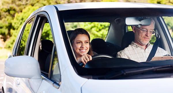 Happy and confident learner driver driving a car with an instructor